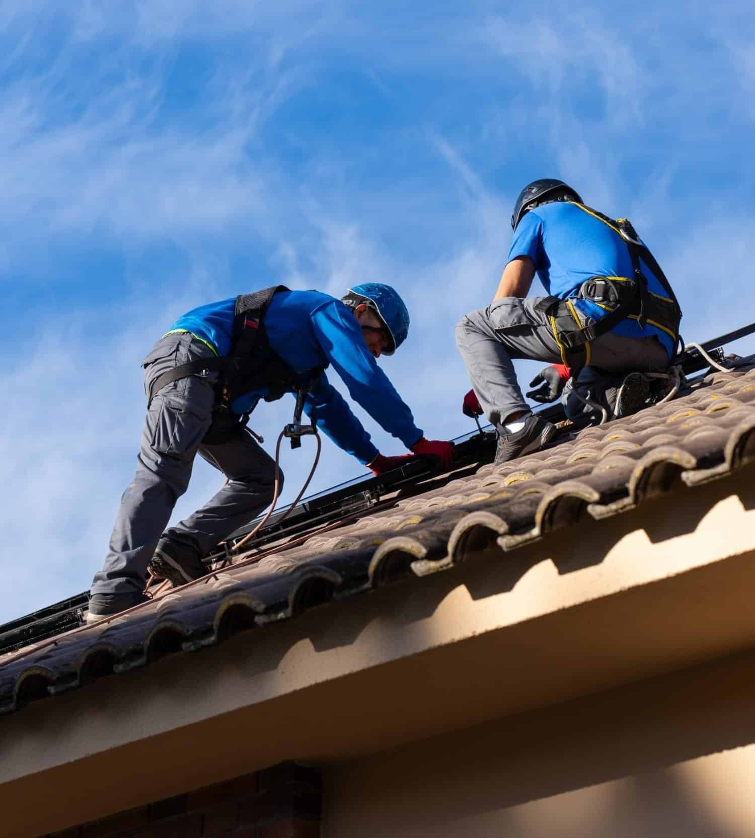 Roofing professionals installing solar panels on a residential roof.
