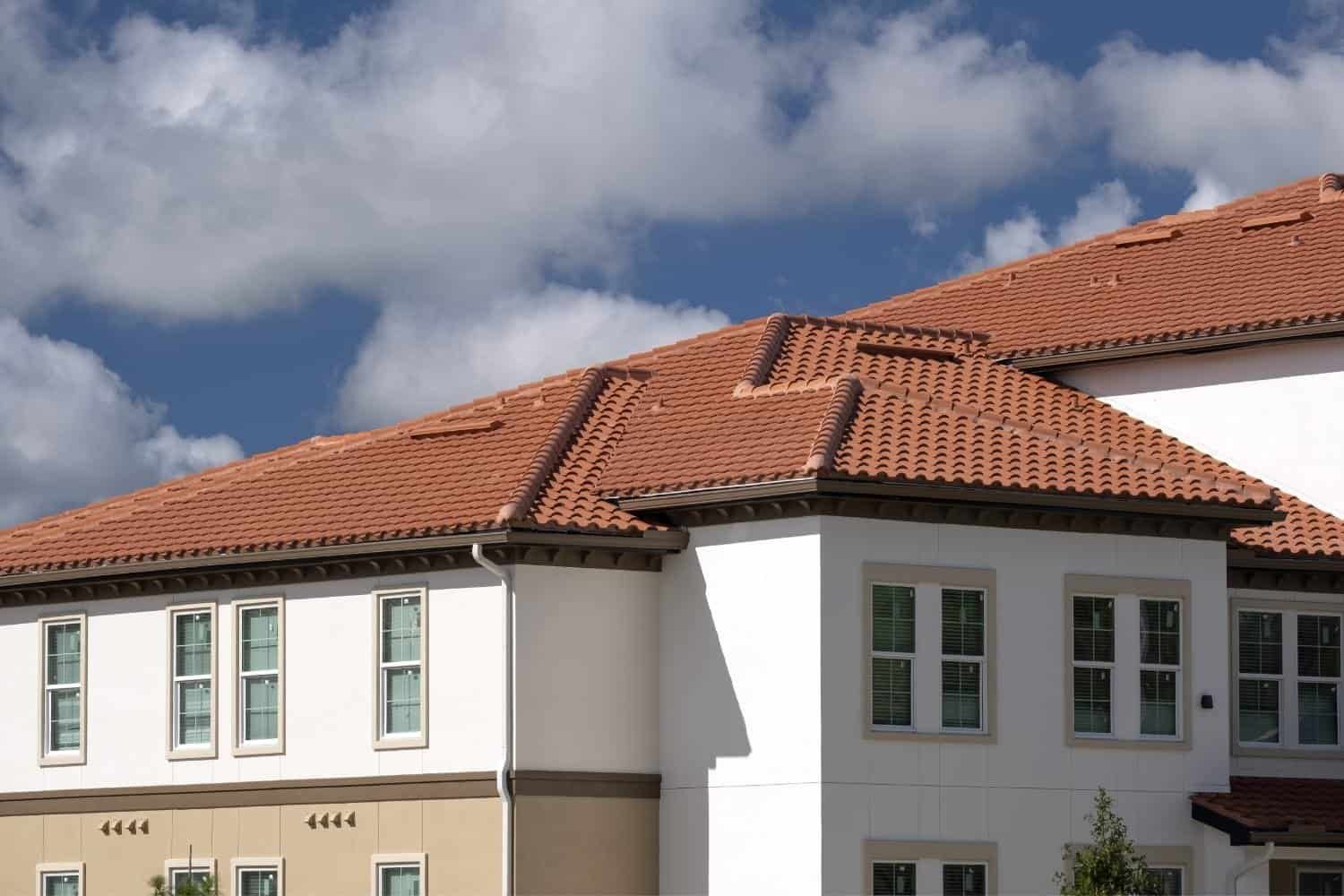 Residential building with red tile roof and white exterior walls.