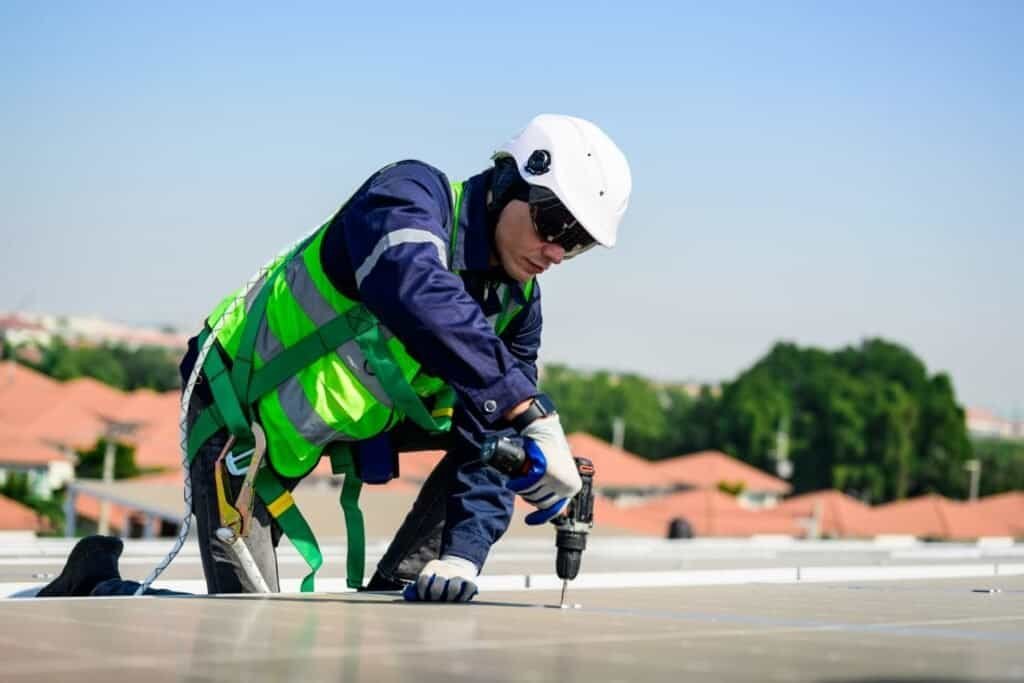 Professional roofer installing solar panels on a residential roof.